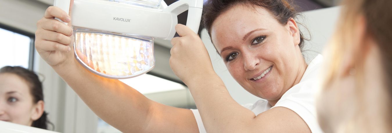 Zahnärztin stellt den Strahler des Behandlungsstuhls ein 