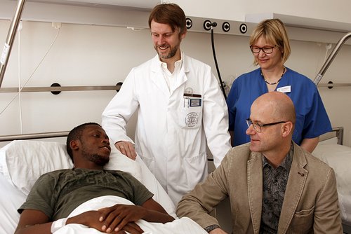Um Luther Erhirhie (links) kümmern sich Prof. Dr. Götz Röderer, Heike Natterer und Matthias Hambücher (sitzend); (Foto: Universitätsklinikum Ulm)