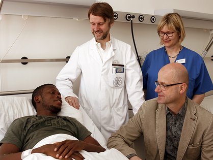 Um Luther Erhirhie (links) kümmern sich Prof. Dr. Götz Röderer, Heike Natterer und Matthias Hambücher (sitzend); (Foto: Universitätsklinikum Ulm)