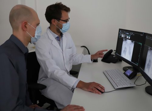 Doktorand Daniel Schaudt und Facharzt Dr. Christopher Kloth analysieren eine Röntgenaufnahme einer Lunge am Computer..