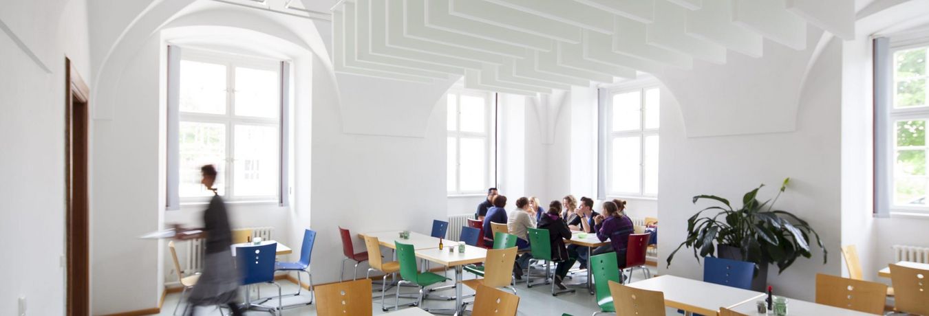 View into a lounge. Several people are sitting at a table eating