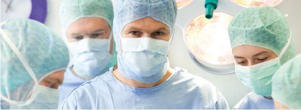 Ärztinnen und Ärzte in OP-Kleidung mit Mundschutz in einem Operationssaal