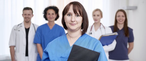 Eine Krankenschwester im Vordergrund, ein Arzt, eine Ärztin und zwei Pflegerinnen im Hintergrund