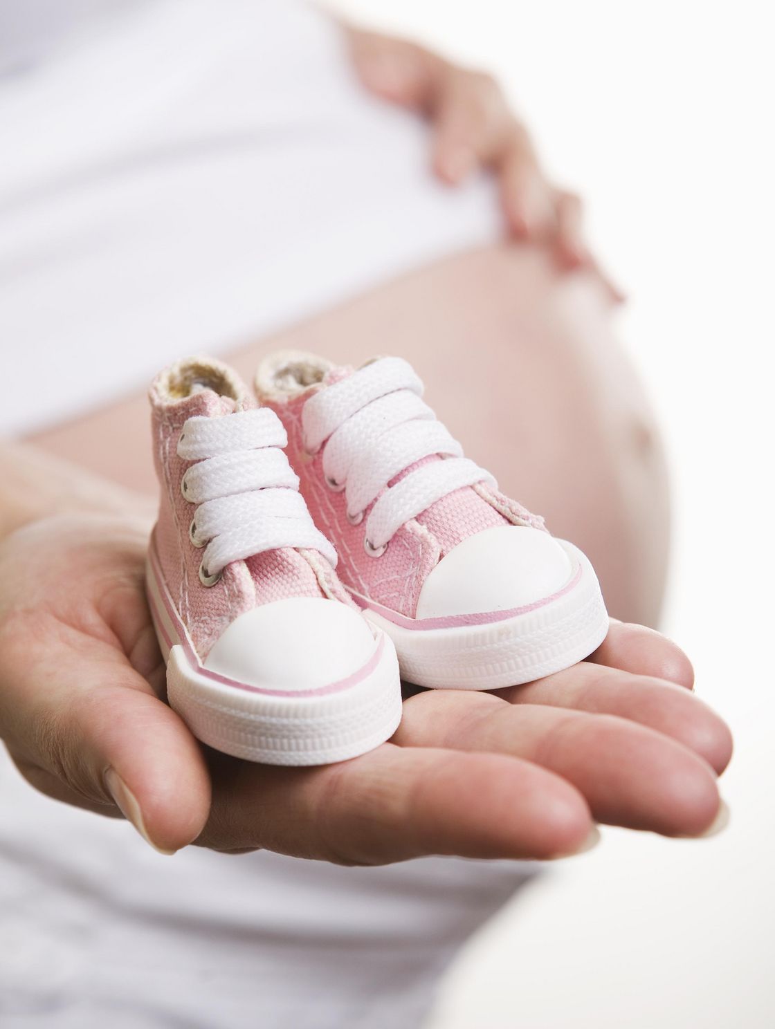 Schwangere Frau mit Babyschuhen in der Hand
