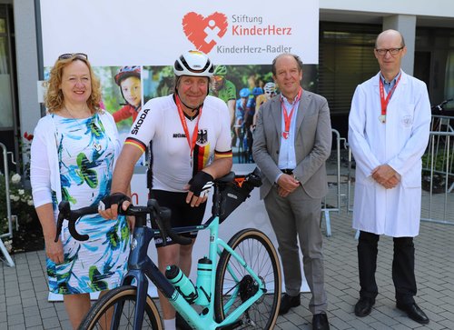 Sylvia Paul, Vorstand Stiftung KinderHerz, Uwe Rohde, Prof. Klaus-Michael Debatin, Ärztlicher Direktor der Klinik für Kinder- und Jugendmedizin und Prof. Christian Apitz, Leiter der Sektion Pädiatrische Kardiologie am UKU stehen beim Besuch des Schauspielers Uwe Rohde vor der Klinik zusammen. 