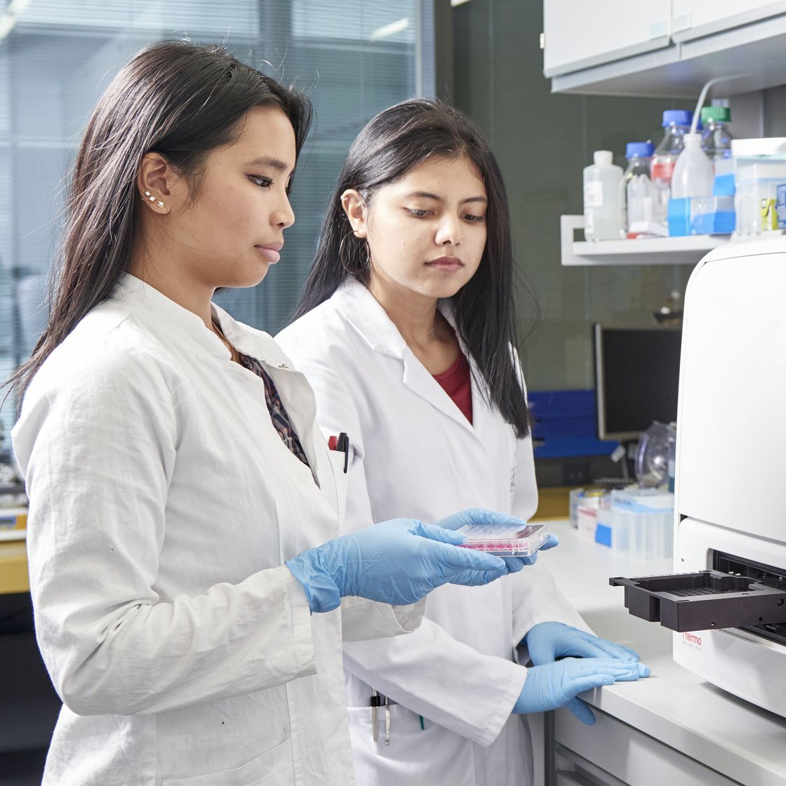 Zwei junge Wissenschaftlerinnen vor einem Gerät im Labor