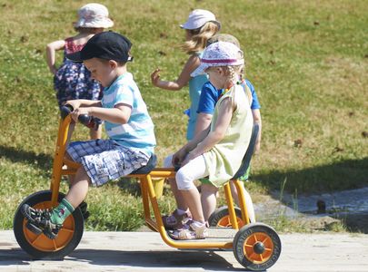 Kinder mit Sonnenhüten auf Kinderdreirädern
