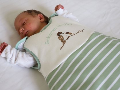 Ein Baby trägt den Babyschlafsack des Universitätsklinikums Ulm