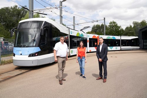 Drei Personen vor der Straßenbahn 