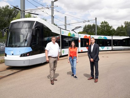 Drei Personen vor der Straßenbahn 