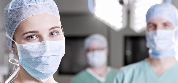 Eine OP-Pflegerin im Vordergrund, iim Hintergrund zwei Kollegen