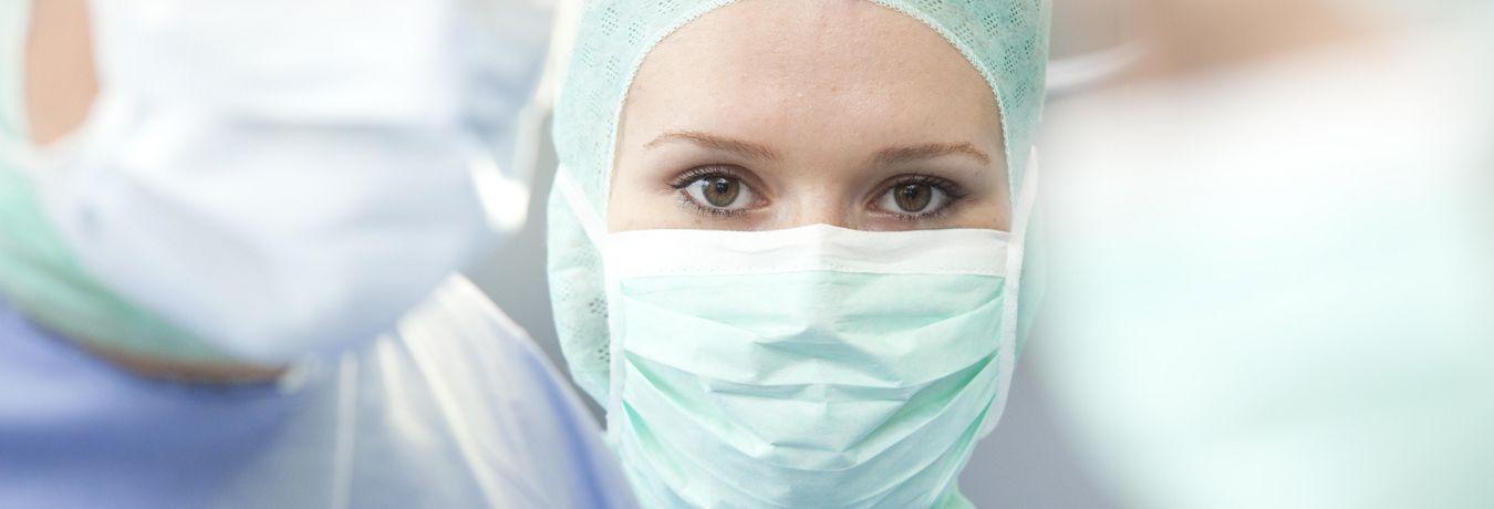 Chirurgin mit Mundschutz und OP-Maske im Operationssaal