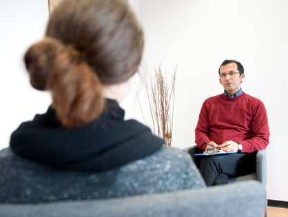 Ein Mann und eine Frau sitzen sich in einer Therapiestunde gegenüber