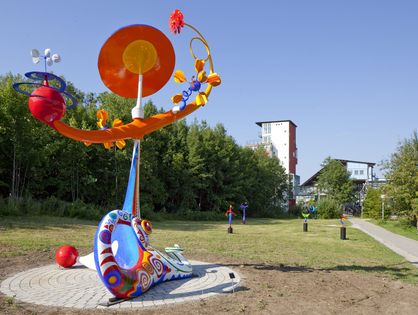 Von links: „Solarika“ mit ihren 19 sonnen- und windangetriebenen Bewegungen (600 x 450 x 254 cm) an ihrem neuen Platz auf dem Oberen Eselsberg; Künstlerin Claire Ochsner vor ihrem restaurierten Kunstwerk (Fotos: UK Ulm).