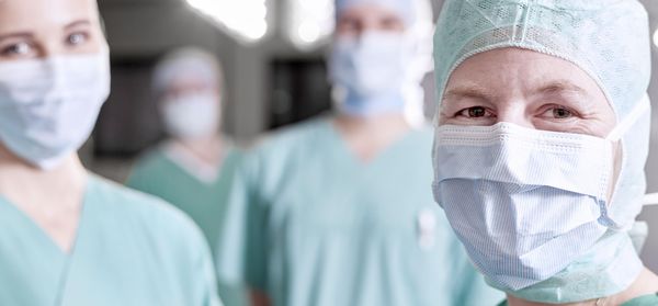 Ein OP-Pfleger im Vordergrund, im Hintergrund zwei Kollegen