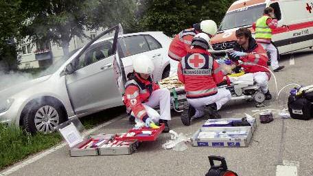 Nachgestellte Szene eines Autounfalls. Rettungskräfte versorgen einen Verletzten