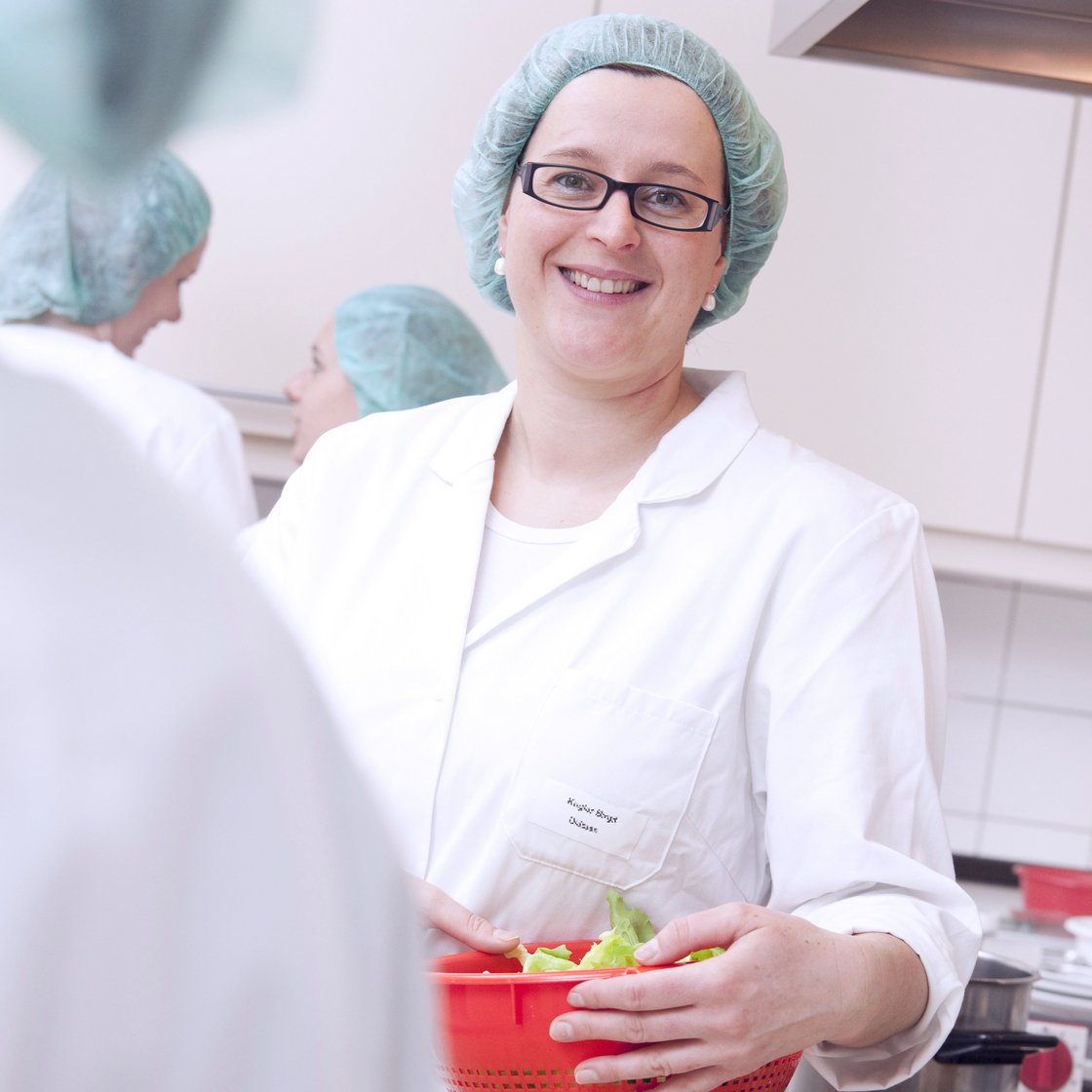 Eine Diätassistentin in der Küche mit einer Schüssel voll Salat in den Händen