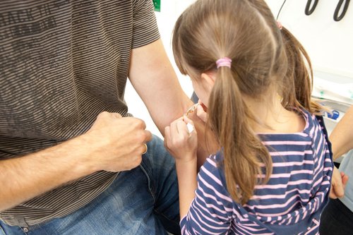 Mädchen klebt seinem Vater ein Pflaster auf den Arm