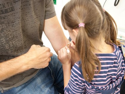 Mädchen klebt seinem Vater ein Pflaster auf den Arm