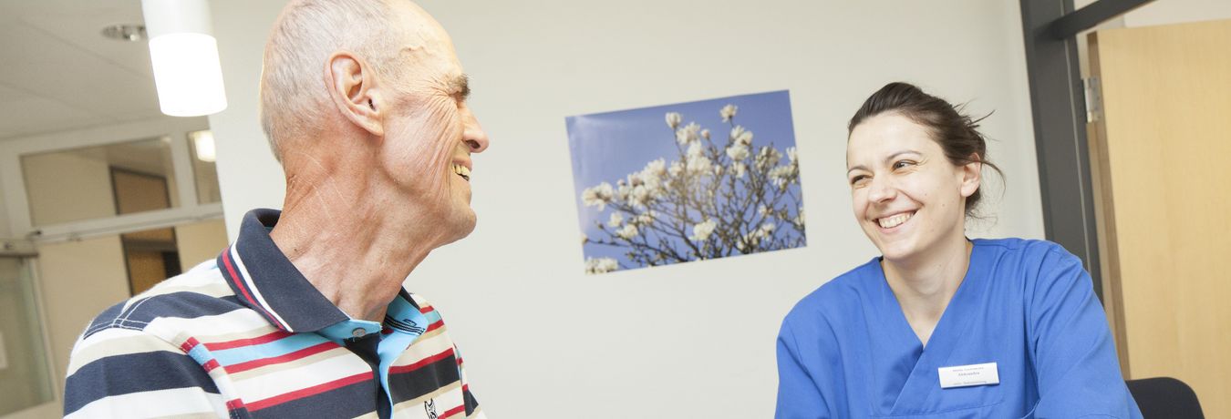 Patient und Pflegefachfrau lachen sich an 