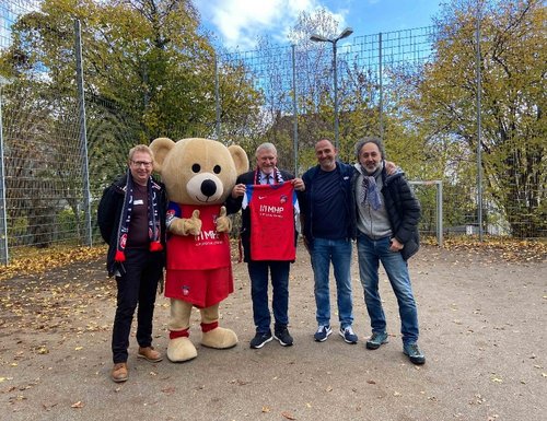 Auf dem Sportplatz der Klinik für Kinder- und Jugendpsychiatrie/Psychotherapie überreichen David Kadel und Frank Schmidt Prof. Dr. Jörg Fegert (2. v.l.) ein von allen Spielern des FCH signiertes Trikot. 